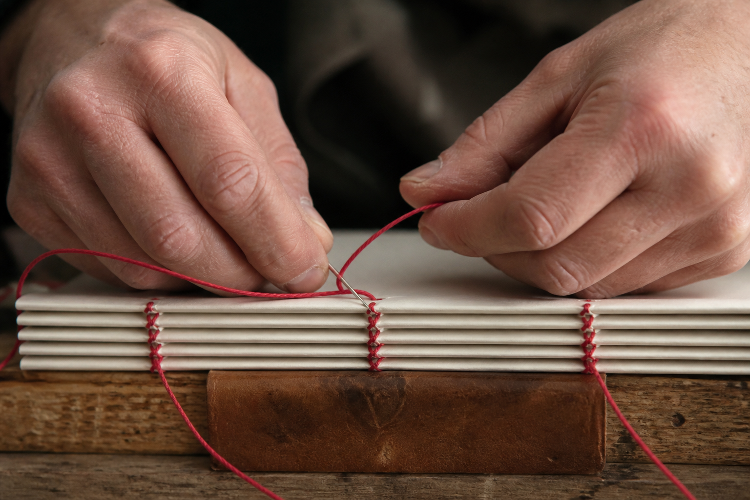 Couture manuelle d'un livre au fil rouge
